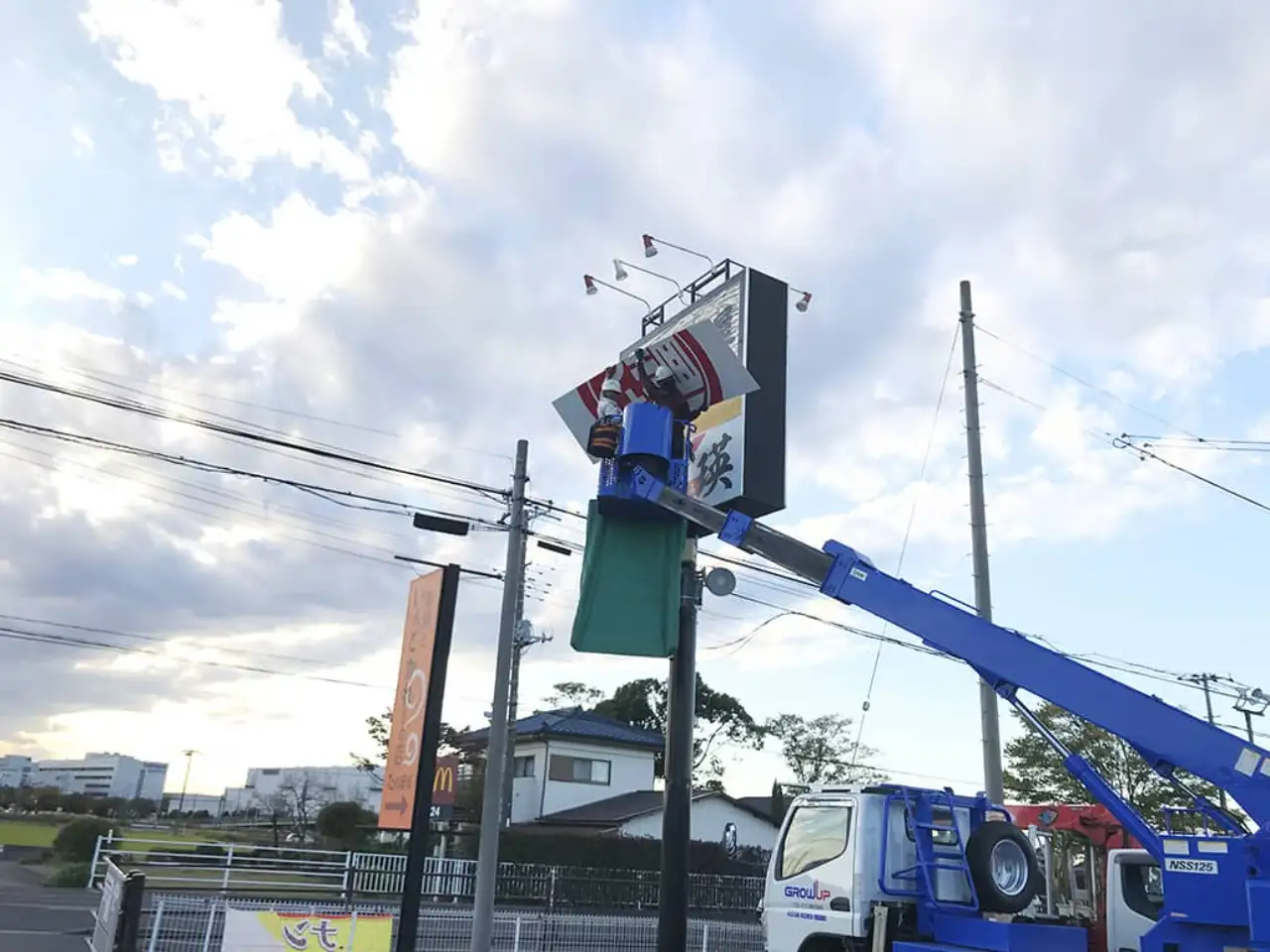 高所作業車でポール看板の面板を交換しているところ
