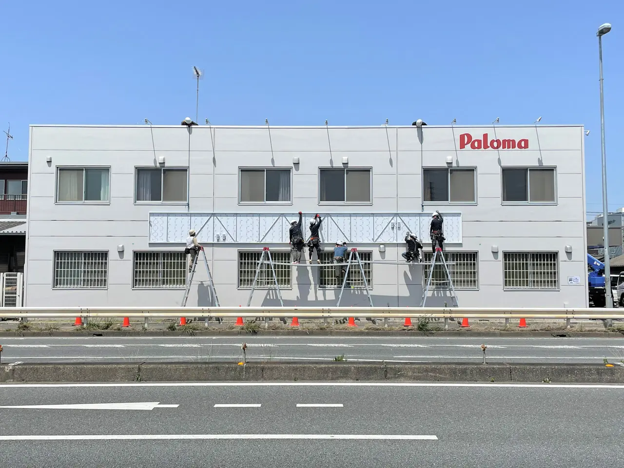 横に長い内照式看板を取り付けているところ