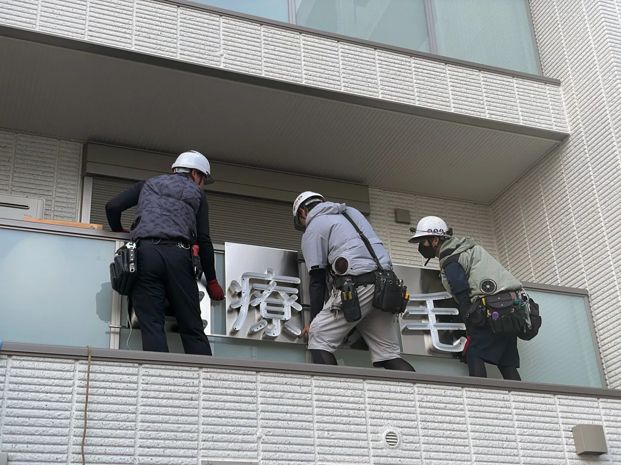 チャンネル文字を手すりに設置しているところ