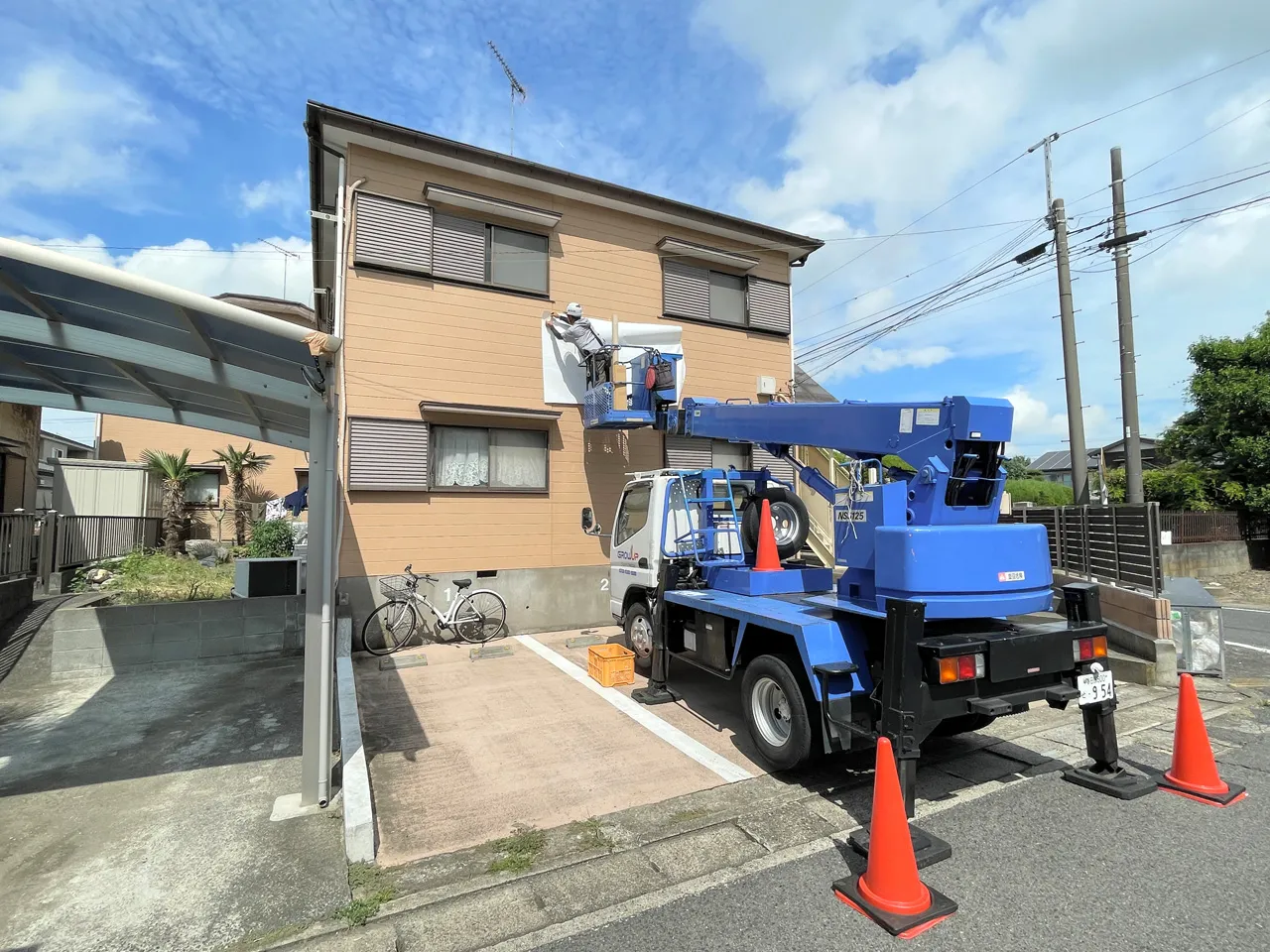 高所作業車で位置合わせの紙を貼っているところ