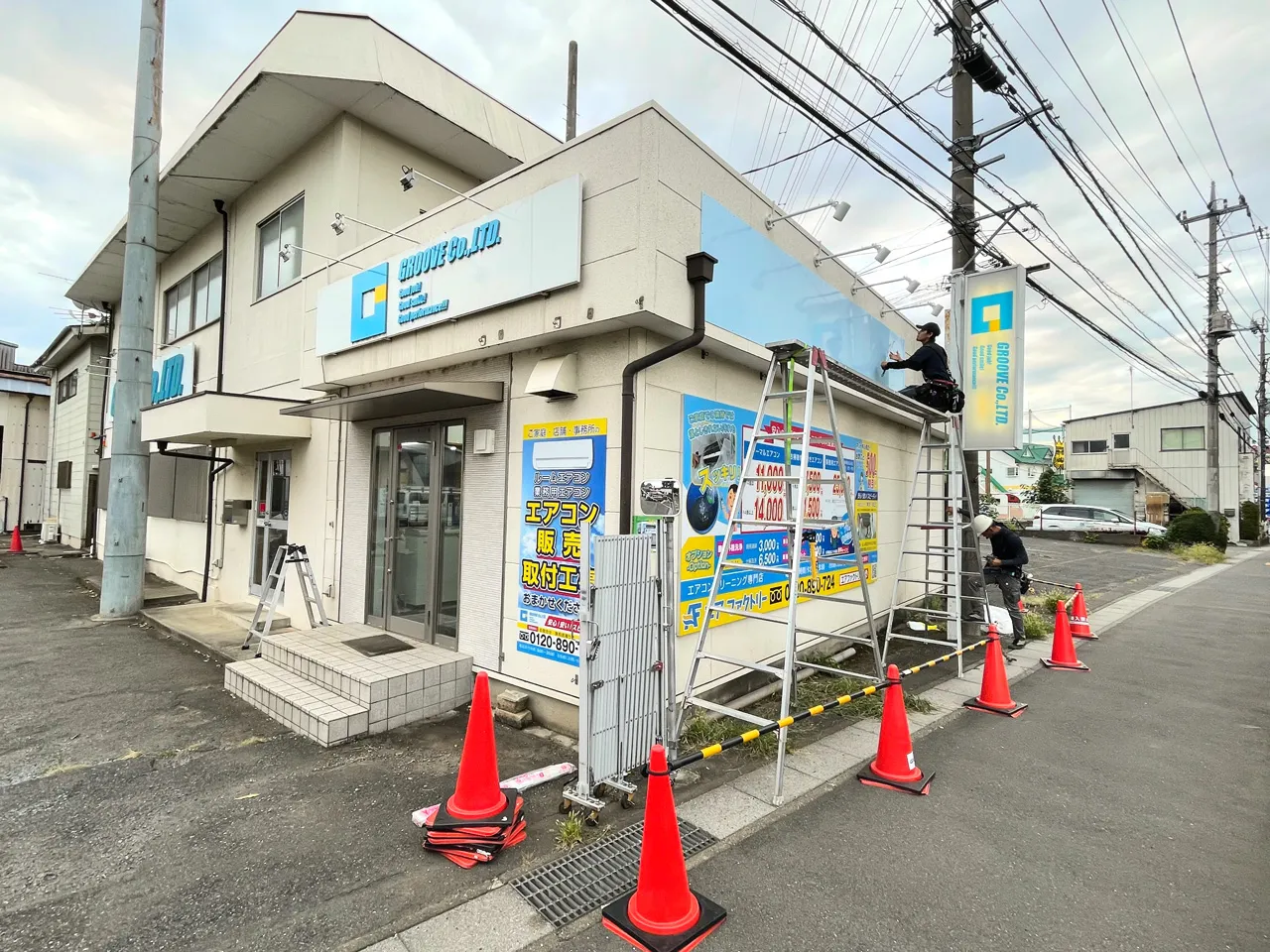 建物側面にカルプ文字とプレート看板を設置しているところ