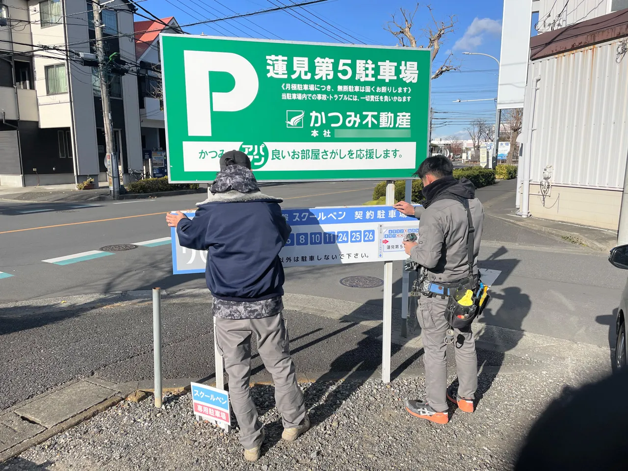 駐車場看板の足にプレート看板を設置しているところ