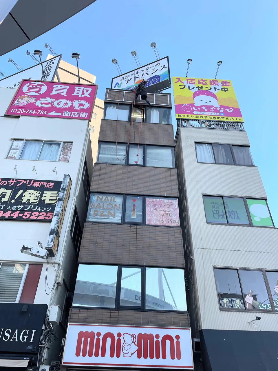 ロープアクセスでプレート看板を壁面に設置しているところ