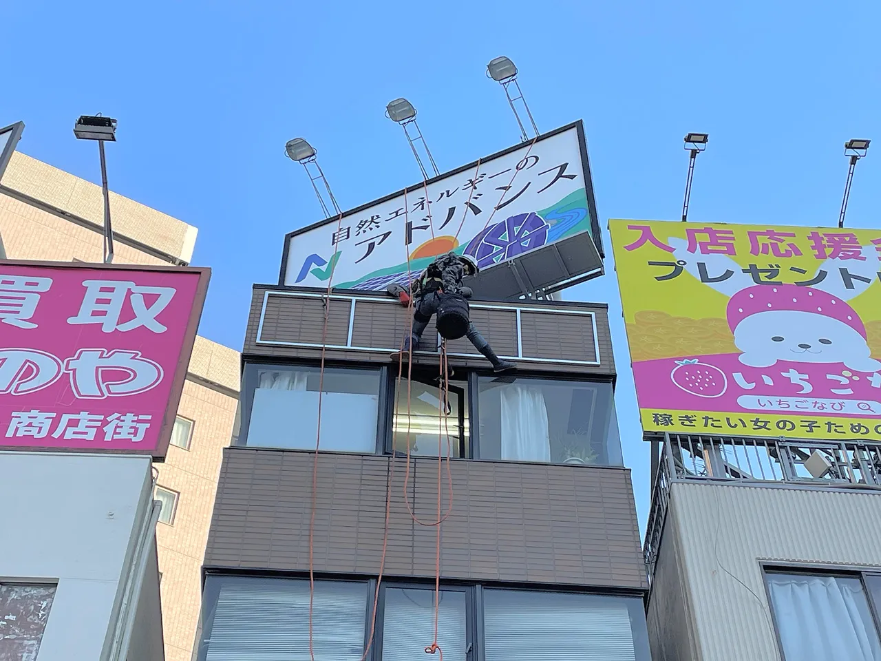 ロープアクセスでプレート看板を壁面に設置しているところ