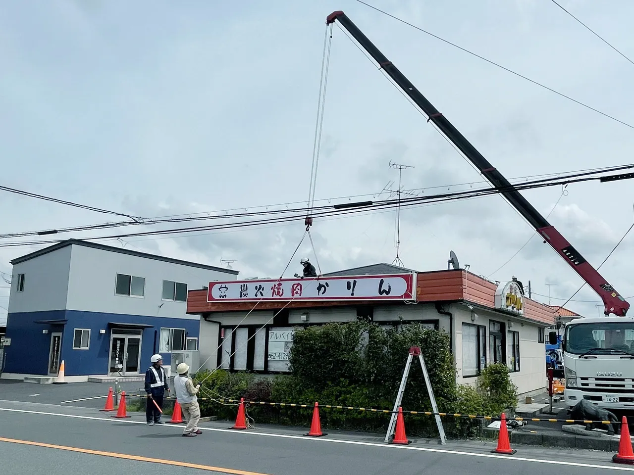 クレーンで看板を吊りながら設置しているところ