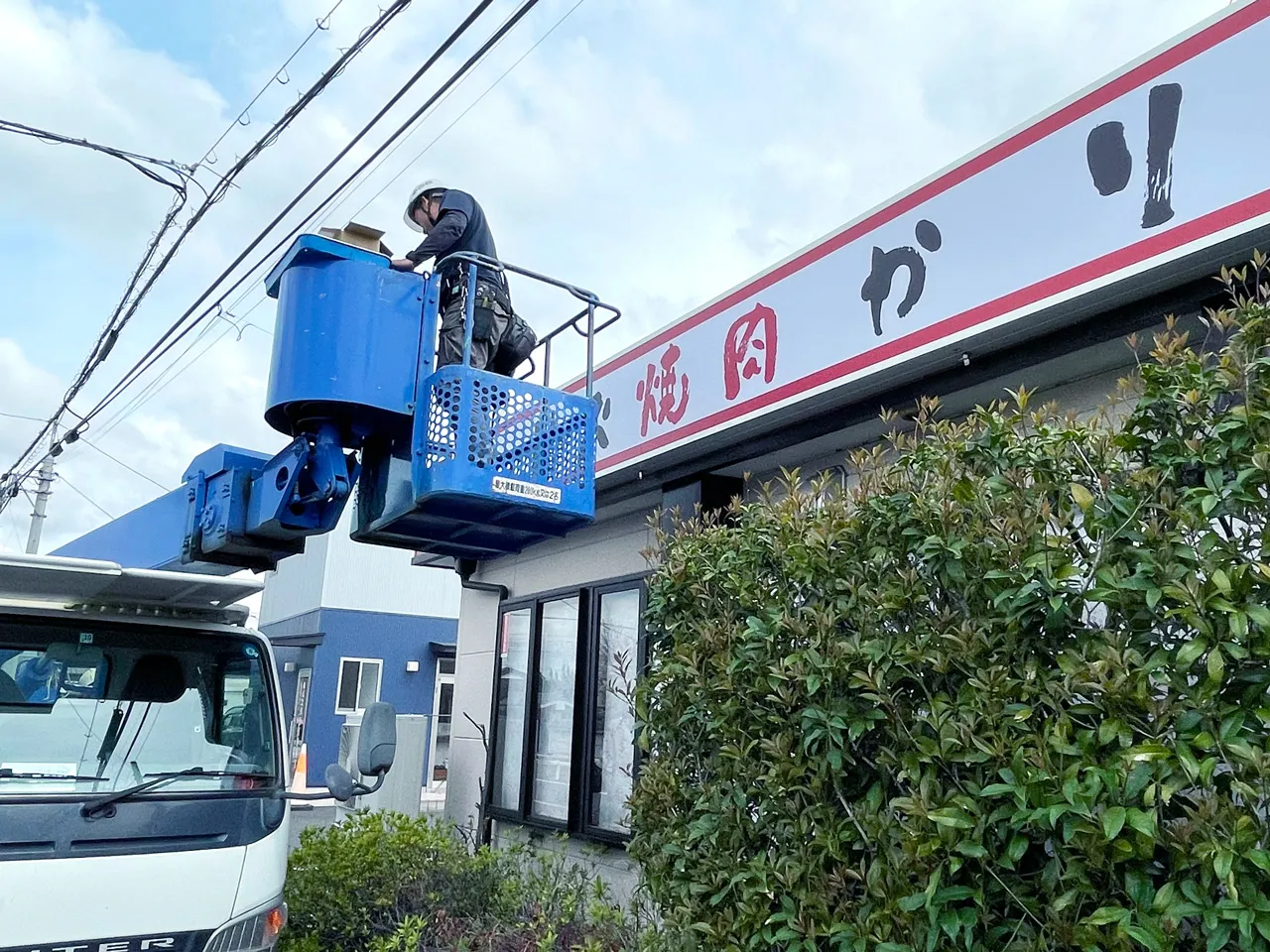 高所作業車で内照式看板を設置しているところ