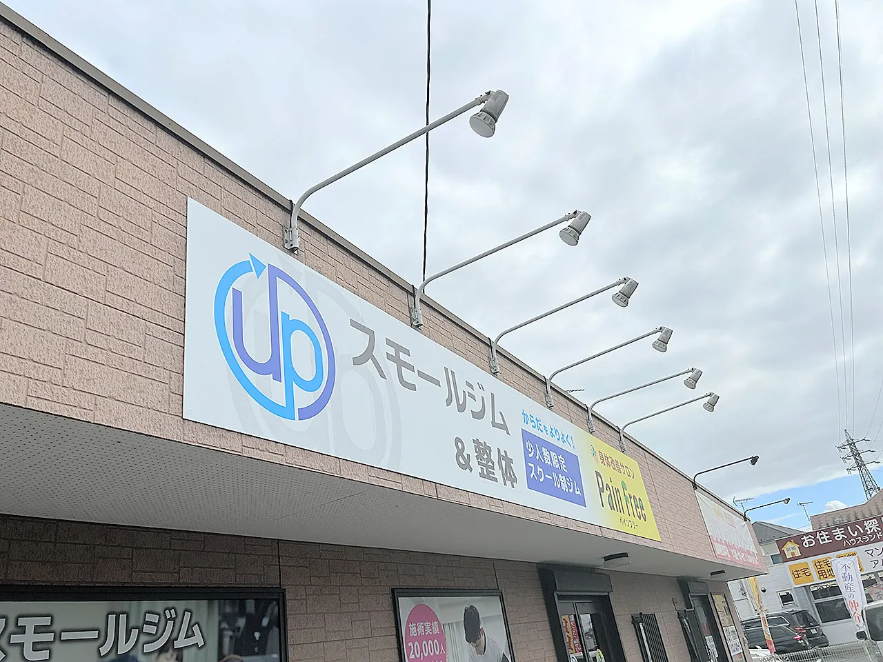 既存の板に上貼りされたプレート看板とスポットライト