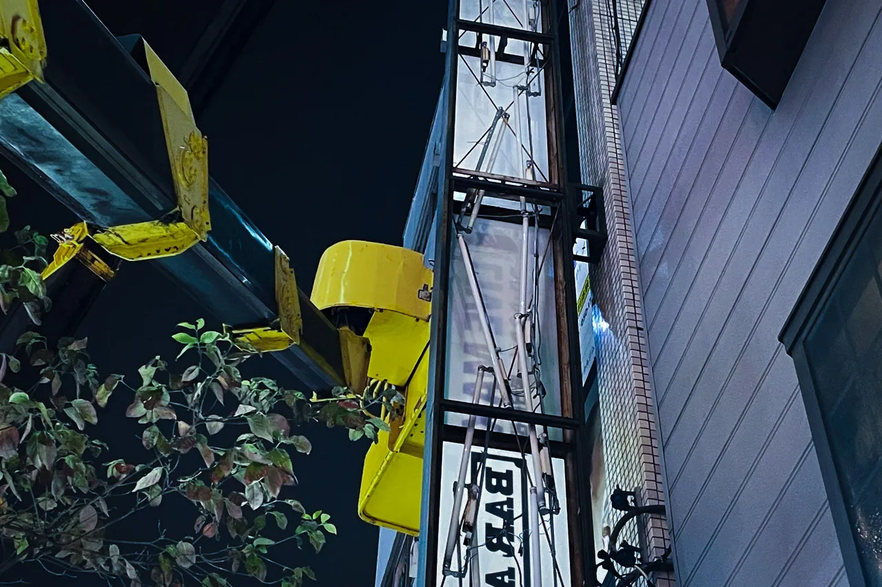 クレーンのフックに袖看板を掛けるところ