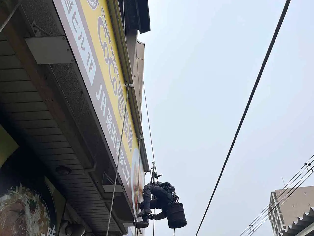 ロープでぶら下がり看板施工しているところ