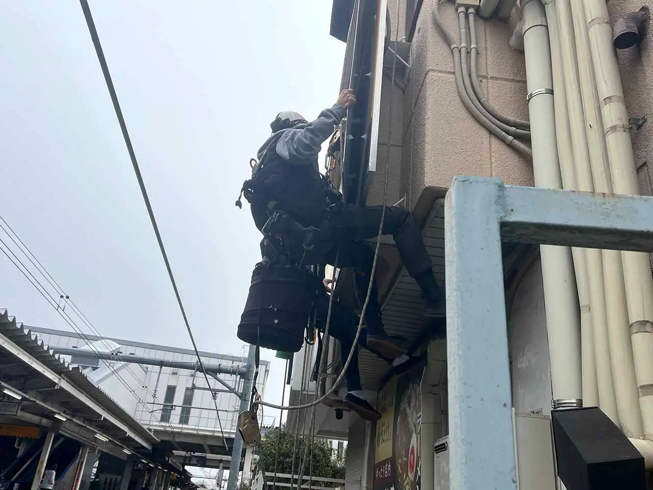 ロープでぶら下がり看板施工しているところ