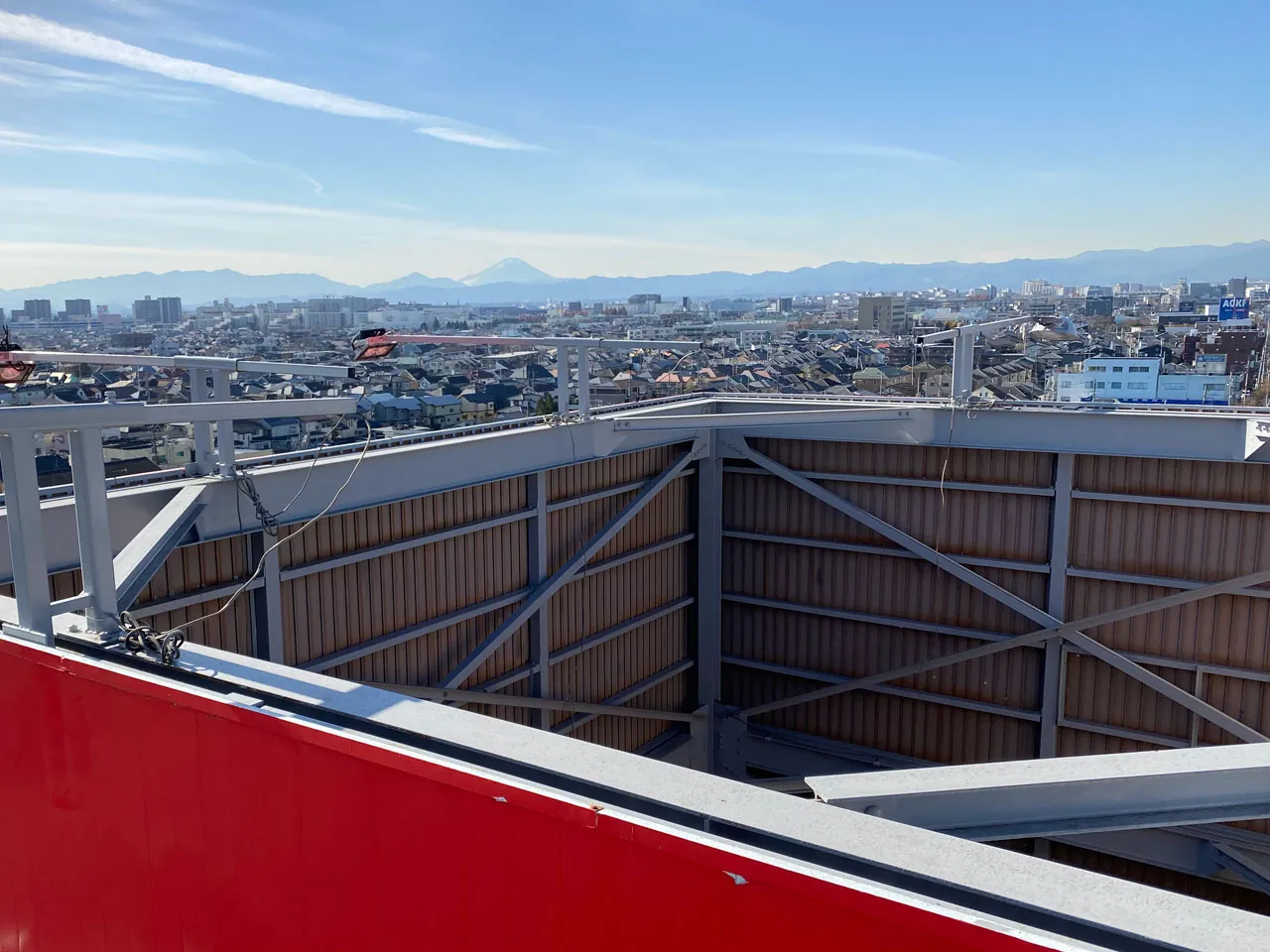 高所作業車を使った塔屋看板のシート貼り