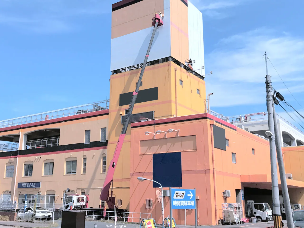 高所作業車を使った塔屋看板のシート貼り