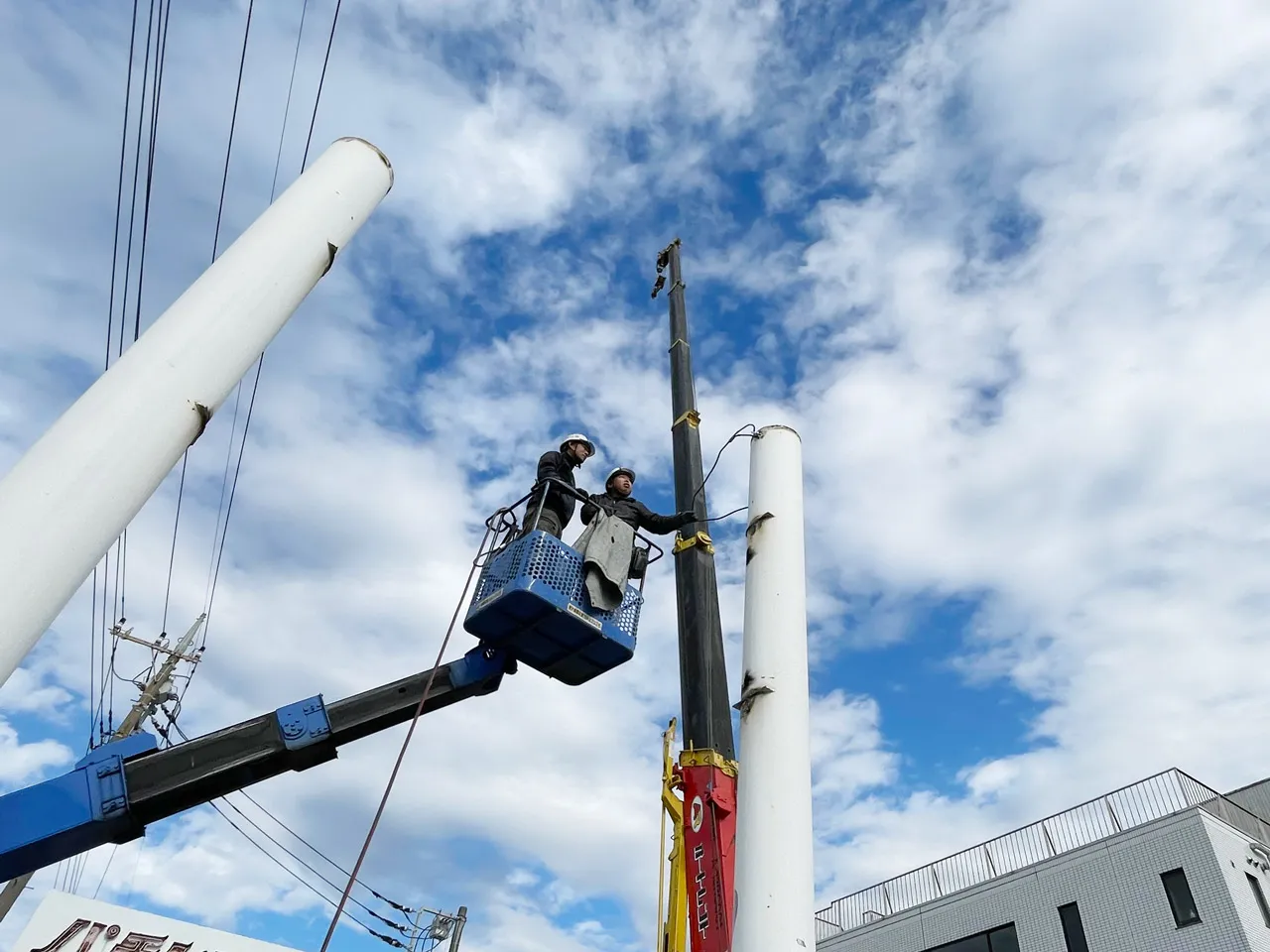 ポール看板の支柱をクレーンで吊る準備